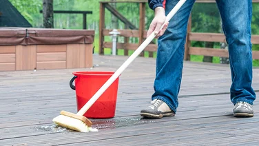 How to clean your decking and patio without a pressure washer man washing decking with a broom and soapy water