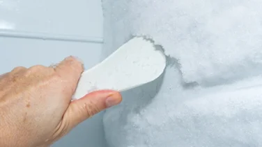 How to defrost a freezer hand using a scrapper to get rid of ice