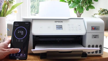 A colour printer being tested by a man holding a smartphone