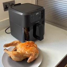 A cooked chicken on a plate, alongside the Instant Pot Vortex Compact 5L air fryer