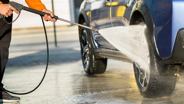 Close-up of person pressure washing SUV wheels
