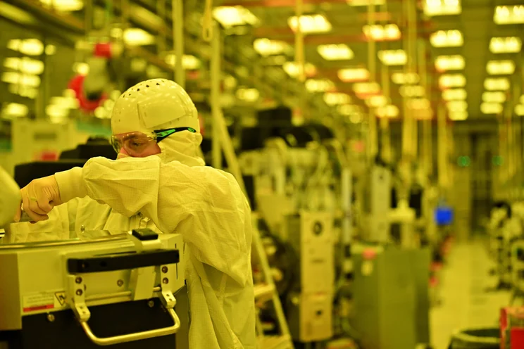 A photograph of an Intel factory worker operating a machine inside Fab 52, Intel's new 18A manufacturing facility in Arizona
