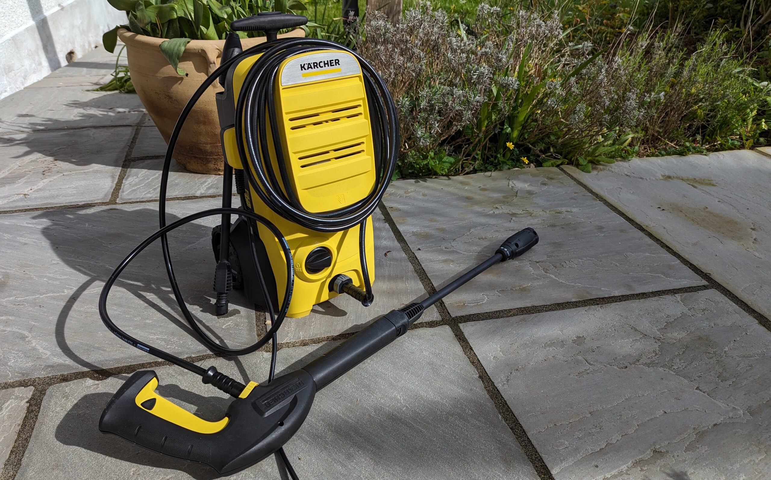 Karcher K4 Classic pressure watcher on stone patio in front of flowerpot with lance lying in front