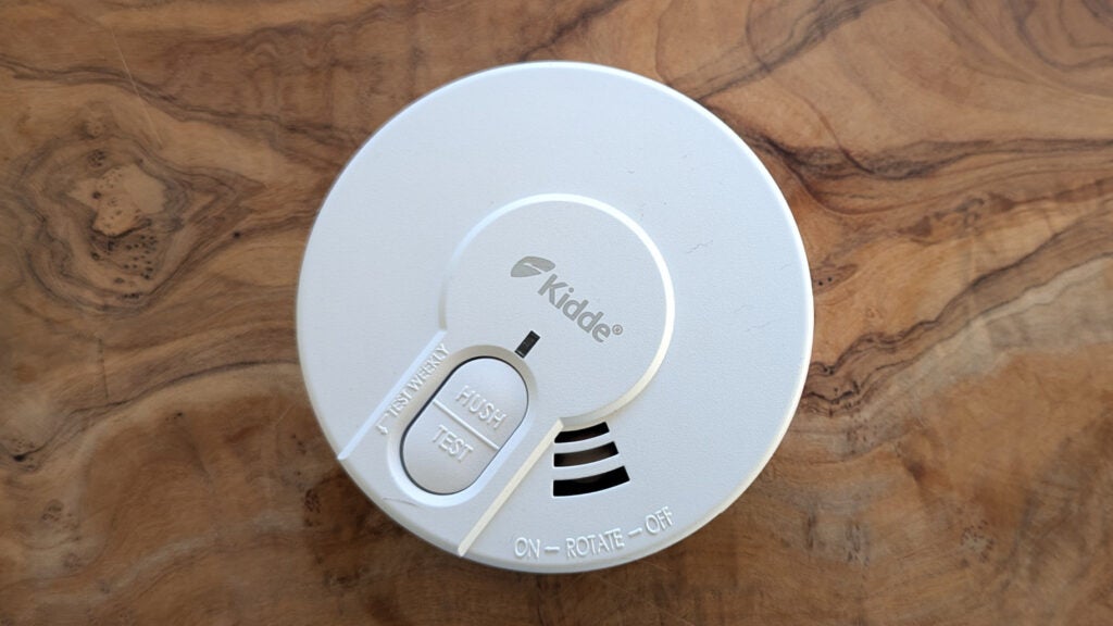 The Kidde DY29 smoke alarm, pictured on a wood surface from above