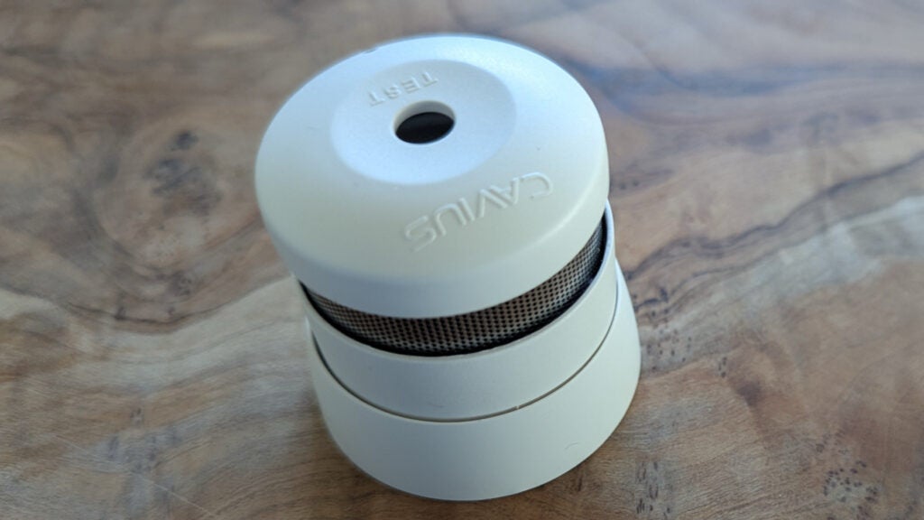 The Kidde K2007 mini smoke alarm pictured on a wood surface 