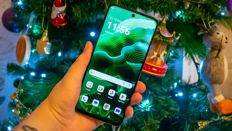 Motorola Moto G35 5G in hand, front view with the display on, in front of a Christmas tree