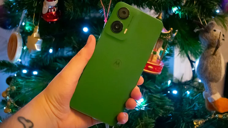 Motorola Moto G35 5G in hand, rear view, in front of a Christmas tree