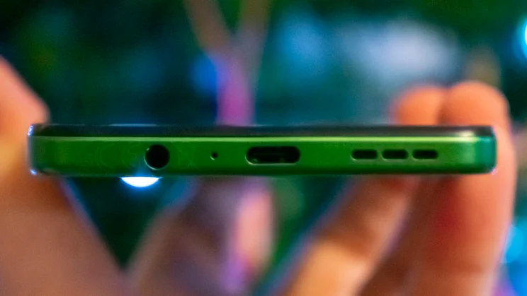 Motorola Moto G35 5G in hand, showing the bottom edge and charging port, in front of a Christmas tree