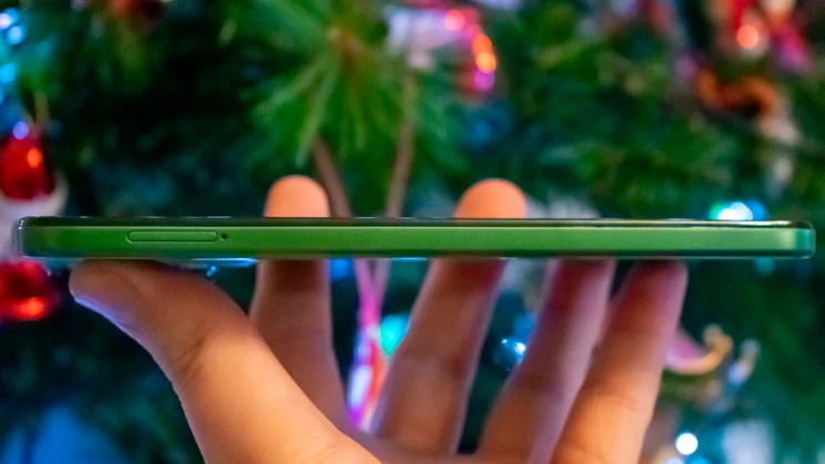 Motorola Moto G35 5G in hand, side view, in front of a Christmas tree