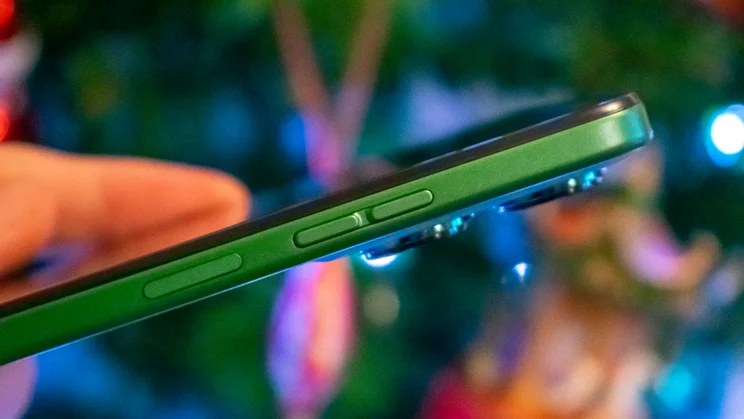 Motorola Moto G35 5G in hand, showing the power and volume buttons, in front of a Christmas tree