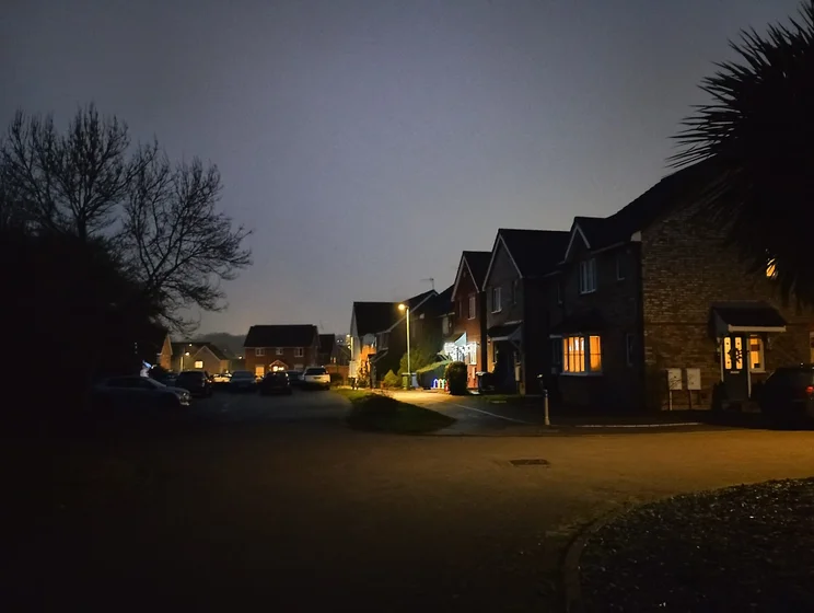 A quiet close at night, houses on the right, trees on the left