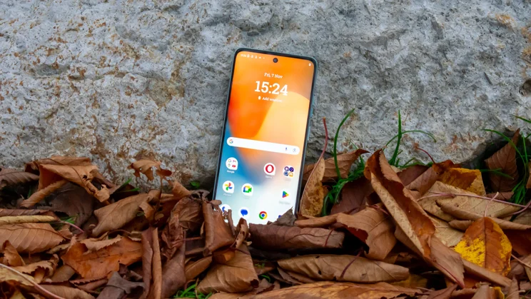 Motorola Moto G56 leaning against a rock, surrounded by leaves, front view