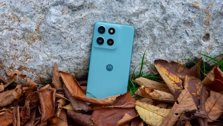 Motorola Moto G56 leaning against a rock, surrounded by leaves, rear view