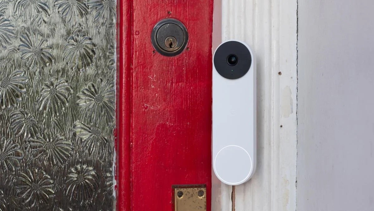 The Nest Doorbell (battery) mounted on a white door frame next to a red front door