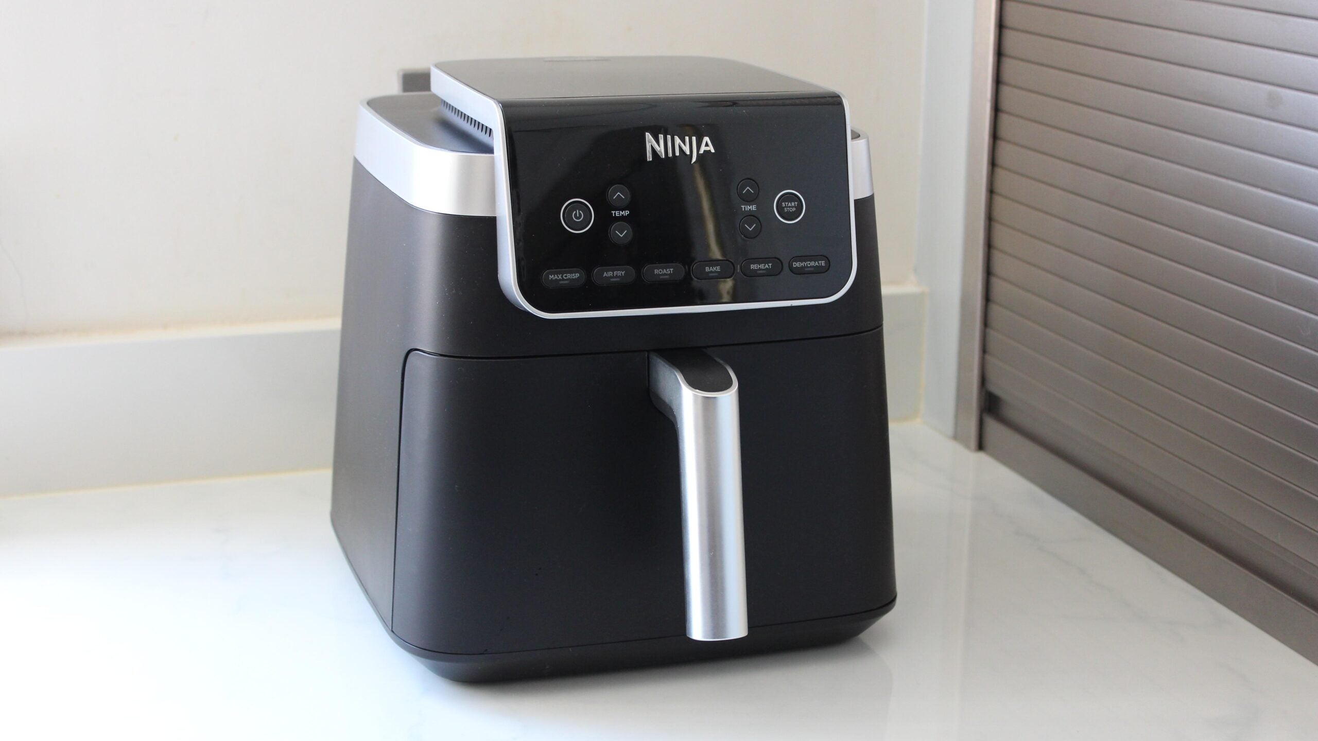 A close up image of a Ninja Air Fryer Max Pro 6.2l AF180UK sitting on a kitchen counter top