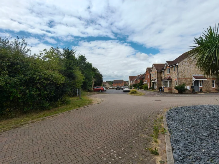 Wide-angle shot of a group of houses with cars parked out front