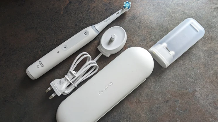 The Oral-B iO4 lying on a surface, alongside its charger, case and brush head case