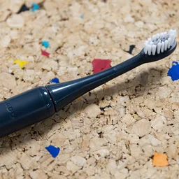 The Ordo Sonic Edge toothbrush laid down on a multicoloured cork table