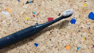 The Ordo Sonic Edge toothbrush laid down on a multicoloured cork table