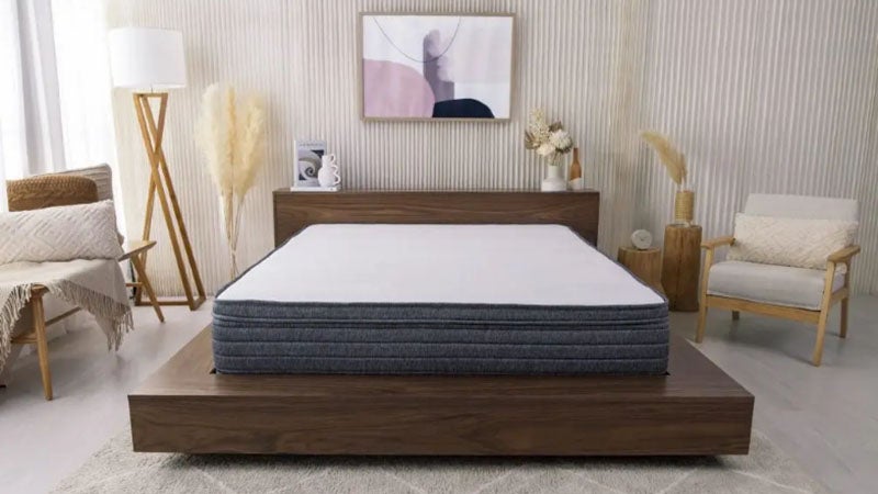 Origin Hybrid mattress on a wooden base next to a lamp and chair