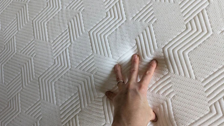 A hand pressing down on the surface of the Panda Hybrid Bamboo mattress