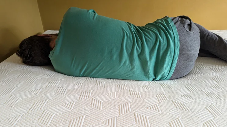A person lying on their side on top of the Panda Hybrid Bamboo mattress
