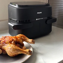 The Philips 1000 Series air fryer on a kitchen worktop, next to a cooked chicken