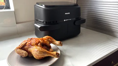 The Philips 1000 Series air fryer on a kitchen worktop, next to a cooked chicken