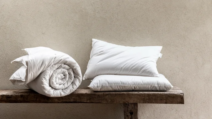 Piglet British wool pillow on a bench with a duvet rolled up