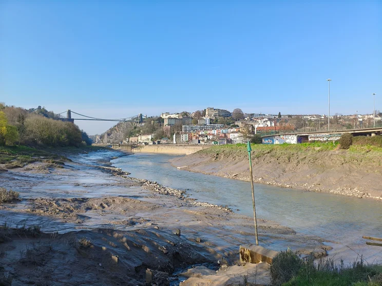 A river at low tide with a bridge in the distance