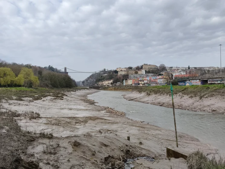 A river at low tide with a bridge in the distance