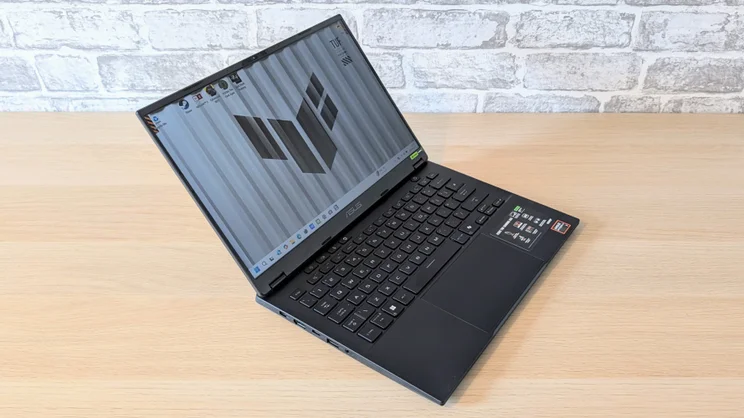 The Asus TUF Gaming A14 RTX 5060 laptop pictured from an angle on a wood desk