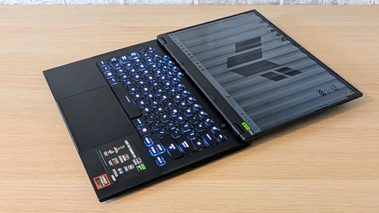 The Asus TUF Gaming A14 RTX 5060 laptop pictured from the front right corner, folded flat on a wood desk