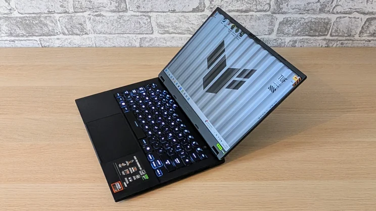 The Asus TUF Gaming A14 RTX 5060 laptop pictured from the front right corner on a wood desk