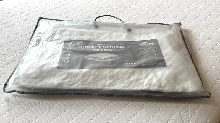 The REM-Fit Deluxe Pocket pillow, vacuum sealed and in its carry bag, on a mattress
