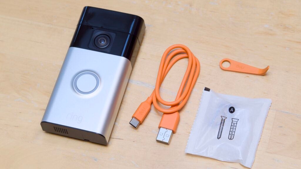 The box contents of the Ring Battery Video Doorbell arranged on a maple wood table