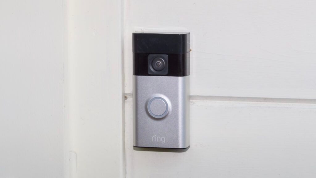 The Ring Battery Video Doorbell pictured mounted on a cream wood wall