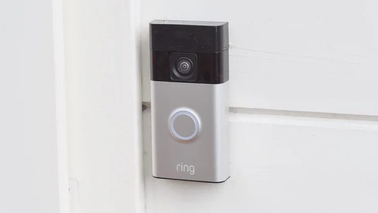 The Ring Battery Video Doorbell mounted on a pale yellow wood wall