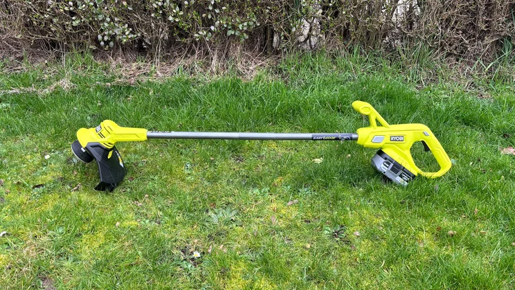Ryobi RY18LT23A-0 grass trimmer - wide shot of trimmer laying on grass