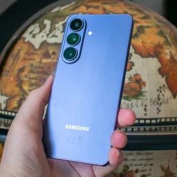 Samsung Galaxy S26 in hand, rear view, in front of a globe