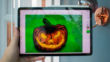Hand holding the Samsung Galaxy Tab S11, front view with a drawing on the display