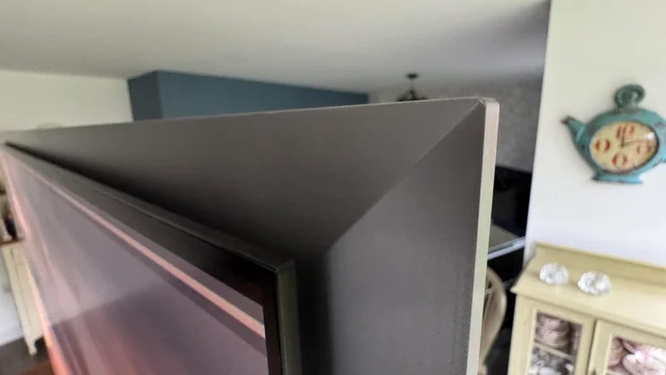 Close-up of the top-right corner of the Samsung S99H quantum dot OLED TV showing the FloatLayer design