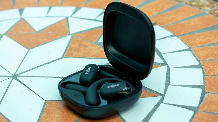 Angled view of the Shokz OpenFit 2 Plus in their charging case, on a mosaic table