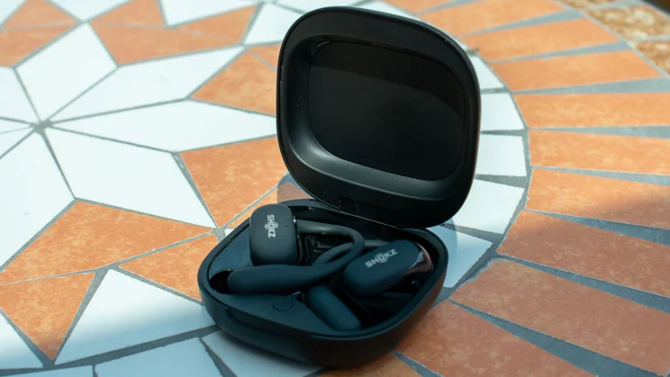 Shokz OpenFit 2 Plus in the charging case, angled view, on a mosaic table