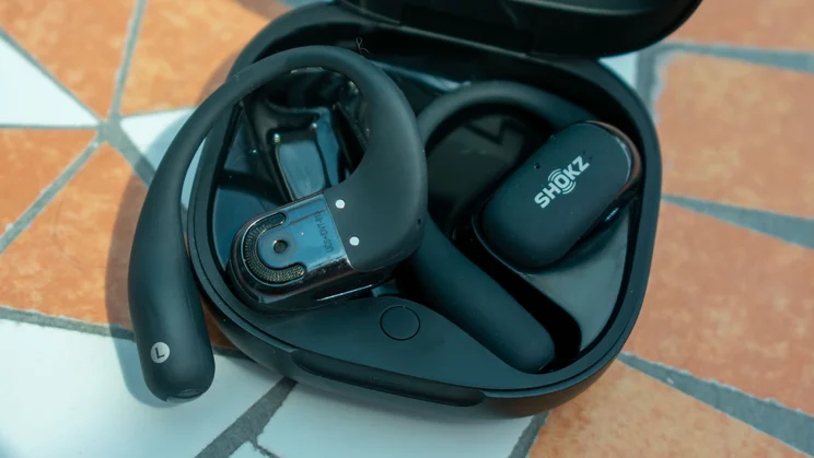 Shokz Open Fit 2 Plus in the charging case, one bud flipped the other way