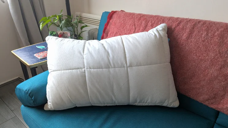 The Simba Aerodown pillow propped up on a sofa