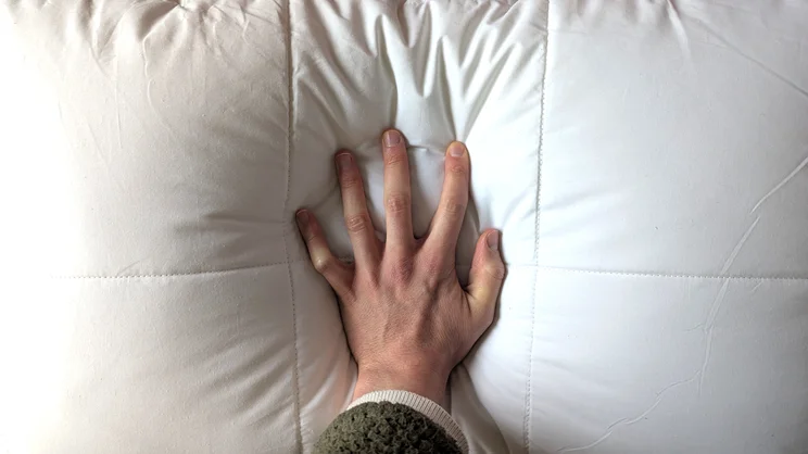 A hand pressing down on the Simba Aerodown pillow's surface