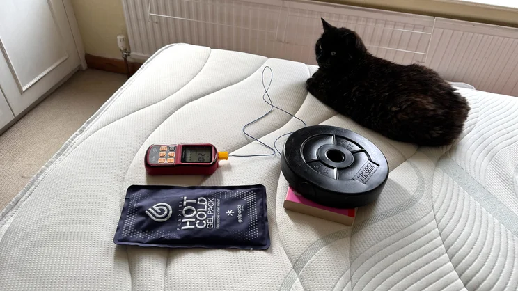 Testing temperature regulation of the Slumberland Air 6.0 Memory mattress. A cat sits next to testing equipment