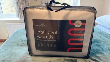 The Snuggledown Intelligent Warmth electric blanket in its bag, on a mattress