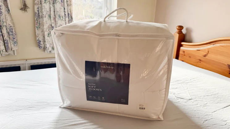The Soak & Sleep Soft as Down duvet in its bag on a mattress